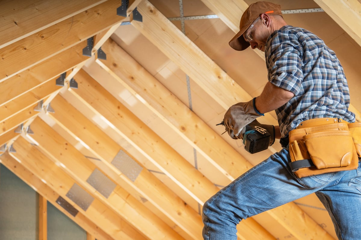 Construction worker installing wooden beams during a property renovation