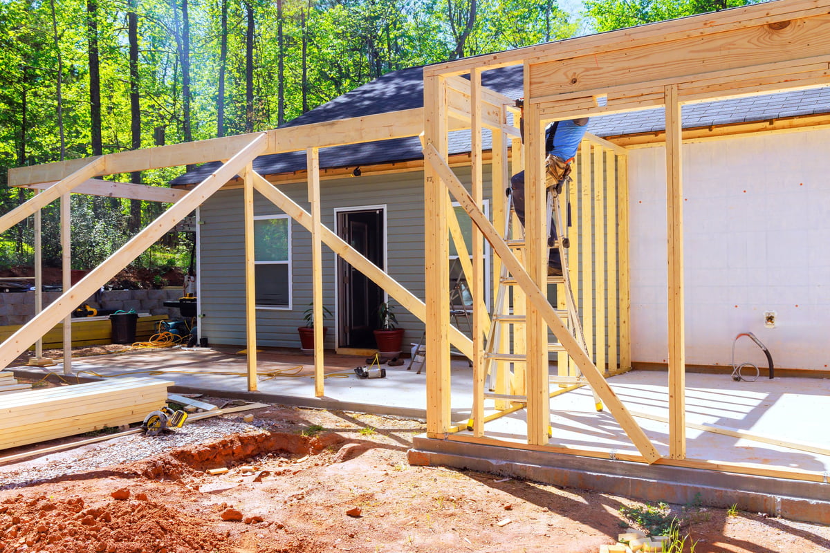 Workers installing wooden roof trusses during a home extension