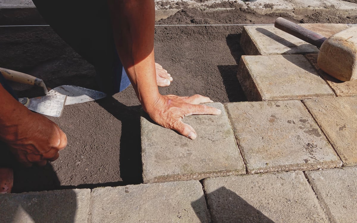 Builder laying paving stones with a mallet on a residential project