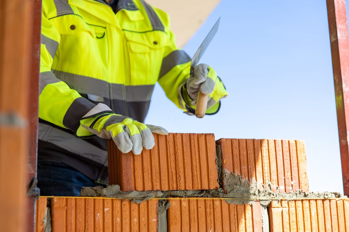 Bricklayer laying bricks with a trowel on a building site in Sheffield